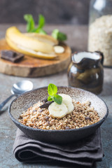 Healthy breakfast bowl. Granola with chocolate and banana on white wooden table. The concept of healthy nutrition and diet.