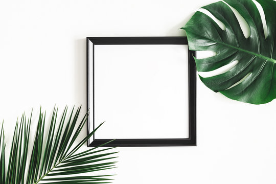 Summer composition. Tropical palm leaves, black photo frame on white background. Summer, nature concept. Flat lay, top view, copy space