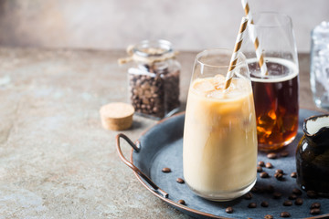 Ice coffee cold summer drink in a tall glass and coffee beans on a stone background.