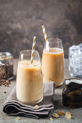 Ice coffee cold summer drink in a tall glass and coffee beans on a stone background.