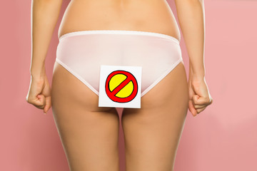 Woman holding prohibition sign in front of her buttocks