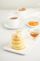 Fried cheese cakes, sweet cheese pancakes on white plate on white background, vertical. Home tea party