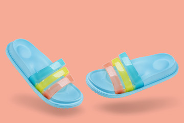 concept of summer and vacation, blue pastel rubber slippers for the shower or for the beach, levitate, on a pink background