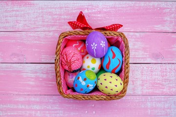 Colorful hand painted easter eggs with pink distress wooden background, pastel color eggs, each...