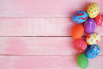 Colorful hand painted easter eggs with pink distress wooden background, pastel color eggs, each with a unique pattern.