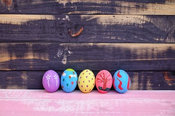Colorful hand painted easter eggs with pink distress wooden background, pastel color eggs, each...