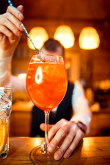 glasses of cocktails on the bar. bartender pours a glass of sparkling wine with Aperol.
