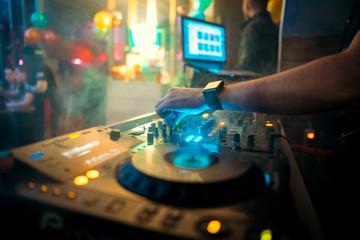 Dj mixes the track in the nightclub at party.  On background of people dancing and a laser show