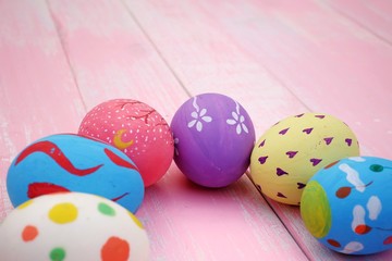 Colorful hand painted easter eggs with pink distress wooden background, pastel color eggs, each with a unique pattern.