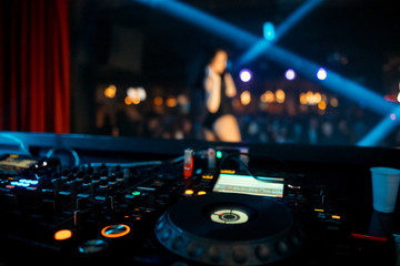 Dj mixes the track in the nightclub at party.  On background of people dancing and a laser show