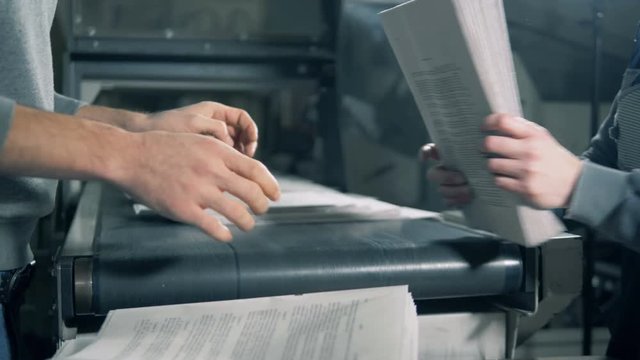 Printed paper is being removed from the conveyor and stacked together