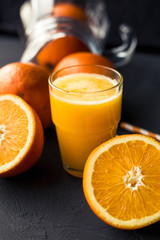 Fresh orange juice and fresh fruit oranges on a black background