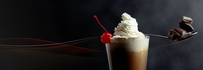 Layered coffee cocktail with whipped cream, cherry and pieces of chocolate.