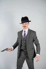vintage English detective with a checkered business suit with a gun on a white studio solid background