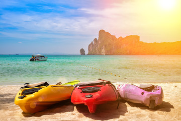 Colorful Kayaks On The Sand. Tropical beach with motor speed boat and cliffs on background. Summer active leisure.