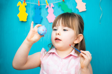 Happy little girl painting easter egg