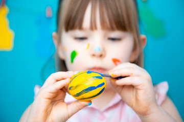 Happy little girl painting easter egg