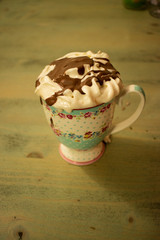 Iced coffee with toasted marshmallow and chocolate syrup Cold coffee drink frappe (frappuccino) with whipped cream and caramel syrup, with straws and grains of coffee on a old antique table. Milkshake
