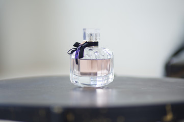 Isolated pink perfume glass bottle on gray table - with black ribbon decoration