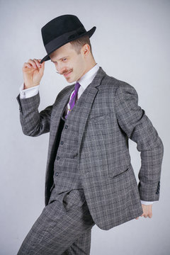 stylish young man in plaid retro business suit and vintage top hat on white solid background in Studio