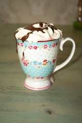 Iced coffee with toasted marshmallow and chocolate syrup Cold coffee drink frappe (frappuccino) with whipped cream and caramel syrup, with straws and grains of coffee on a old antique table. Milkshake