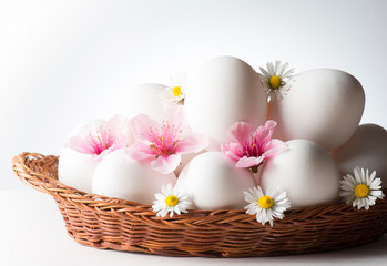 Obraz na płótnie Canvas basket with white eggs and flowers