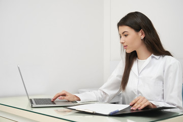 Young woman, doctor working with notebook in clinic.