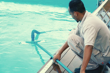 Pool cleaner during his work. Hand african hotel staff worker cleaning the pool. Toning.