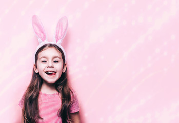 Obraz na płótnie Canvas Cute little girl with bunny ears on pink background. Easter child portrait, funny emotions, surprise. Copyspace for text.