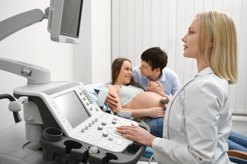 Happy couple on ultrasound exam of pregnant woman.
