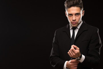 Attractive suited handsome businessman posing on black background adjusting his suit looking to the camera confidently copyspace sexuality seduction success men elegance powerful fierce