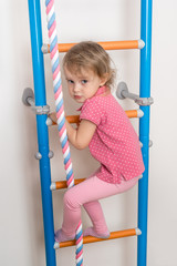Little happy girl climbing the ladder
