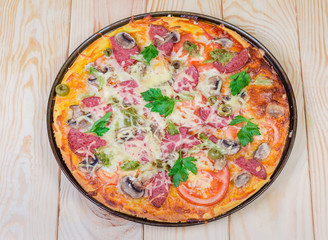 Cooked pizza with salami close-up on rustic wooden table