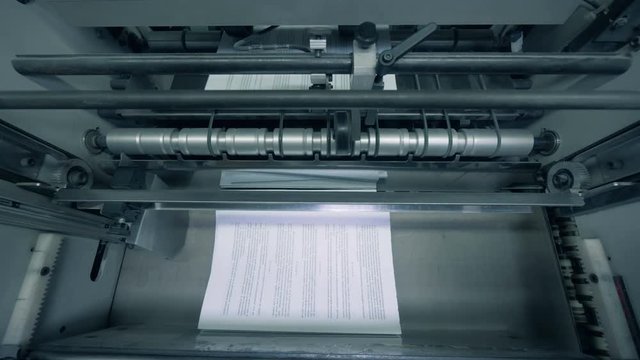 Paper pages with text are getting issued by a factory mechanism in a top view