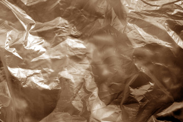 Crumpled transparent plastic  surface in brown tone.