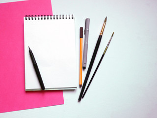 Art table colorful sheets of paper and blank notebook on white background