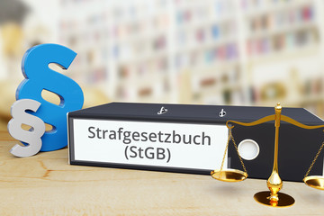 Strafgesetzbuch (StGB) – Anwalt. Ordner auf Schreibtisch mit Beschriftung neben Paragraf und Waage.