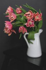 A bouquet of pink peony tulips in a white jug.