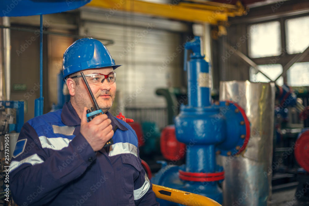 Wall mural plumber inspects piping for heat installation;the mechanic - the repairman tightens bolts on a flang