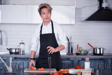 Asian cook in the kitchen prepares food in a cook suit