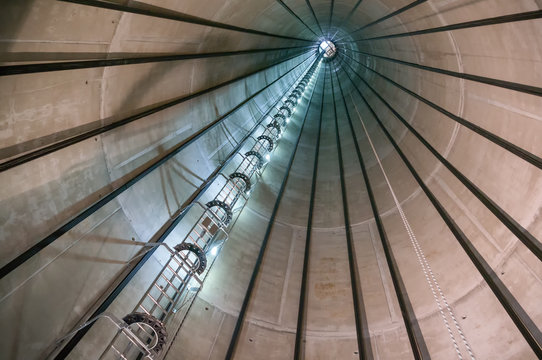 The endless ladder of a wind turbine disappears within the massive concrete hybrid tower