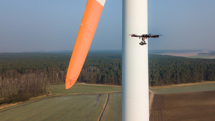 Industrial inspection drone takes photographs of a wind turbine's rotor blades.