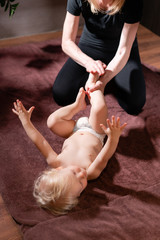 Baby massage. Mother or therapist makes massage to her baby at home. Health care and medicine concept. Blond boy