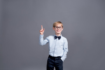 little boy in glasses posing on grey background