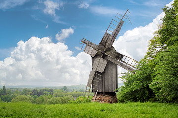 Fototapeta na wymiar Old destroyed wooden windmill, on the background of a beautiful rustic summer landscape