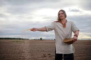 A young peasant sows the field with grain