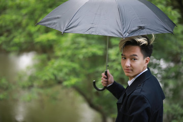 Spring rainy weather and a young man with an umbrella