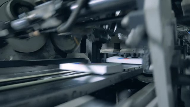 Factory machine is cutting off edges of printed books