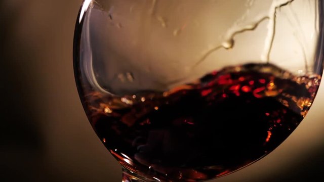 Cognac is rotated in a glass. On dark background.