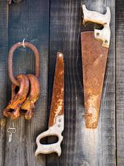 old rusted vintage saw and tools hanging on a barn